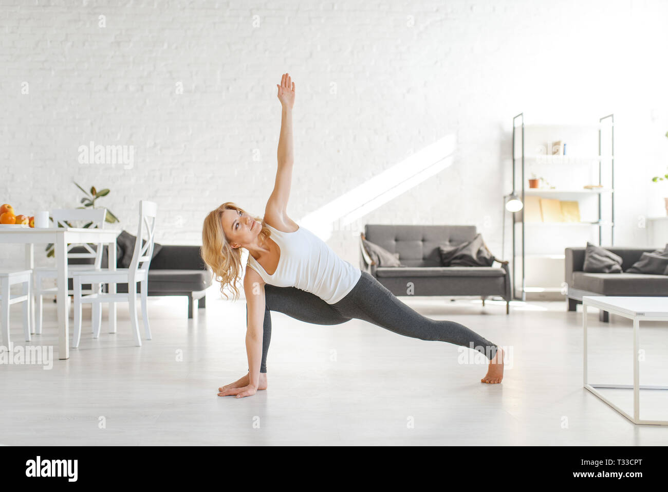 Yuong woman sitting on the floor in yoga pose, living room interior in ...
