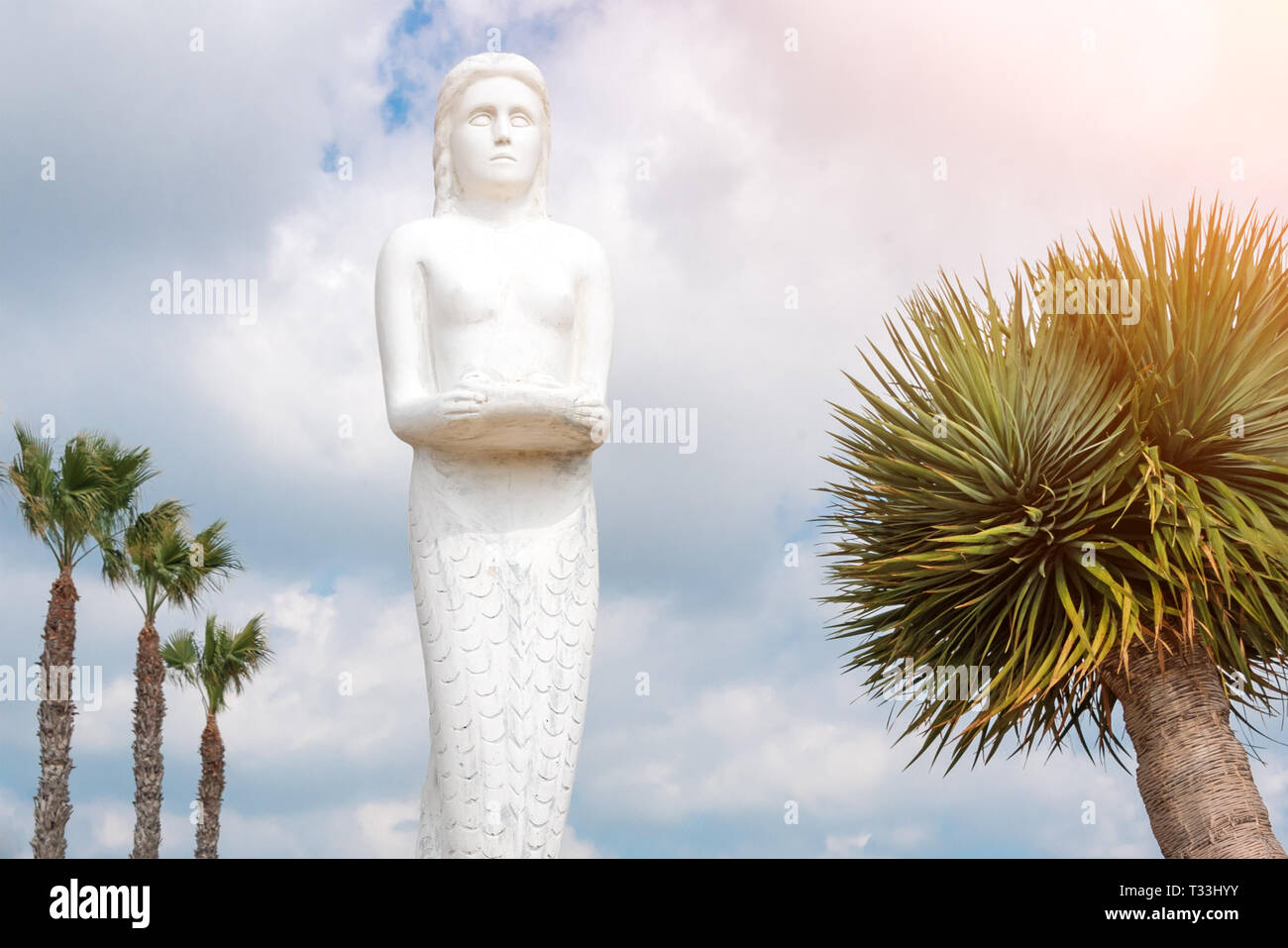 Mermaid statue in the park among palm trees. Stock Photo