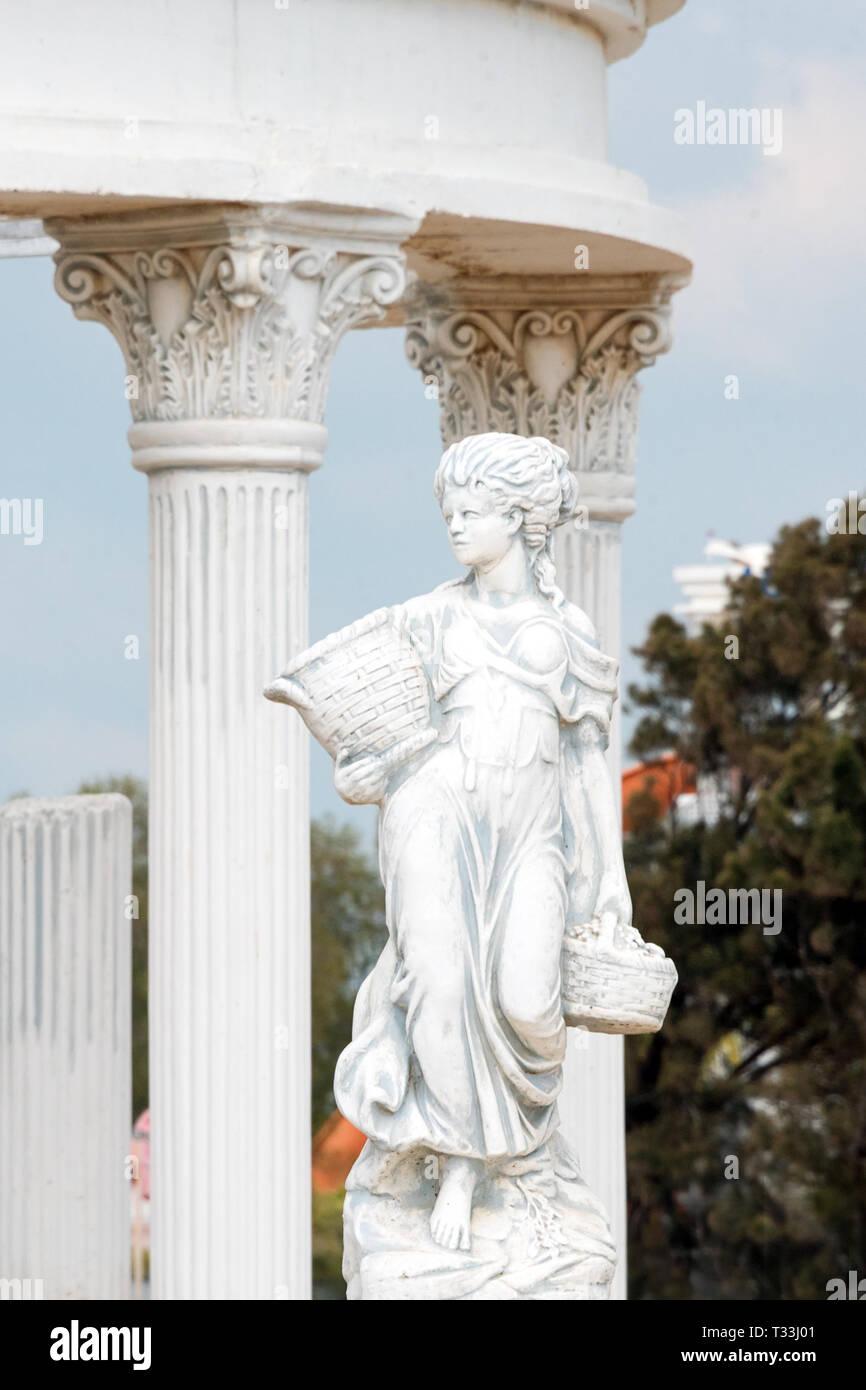 Sculpture of young woman holding basket full of grapes or fruits near