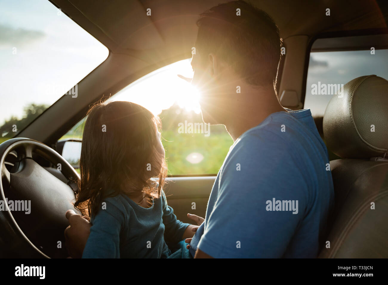 dad and daughter enjoy sunset inside car Stock Photo