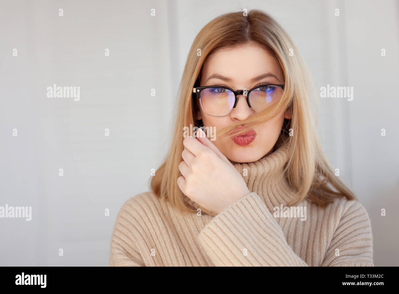 Charming young girl in a glasses. Young woman Makes air a kiss. Close
