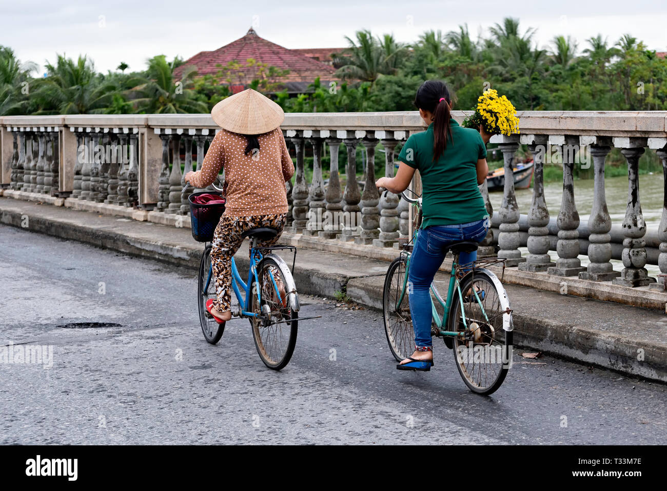 Women riding bike on the bridge in Hoi An Stock Photo