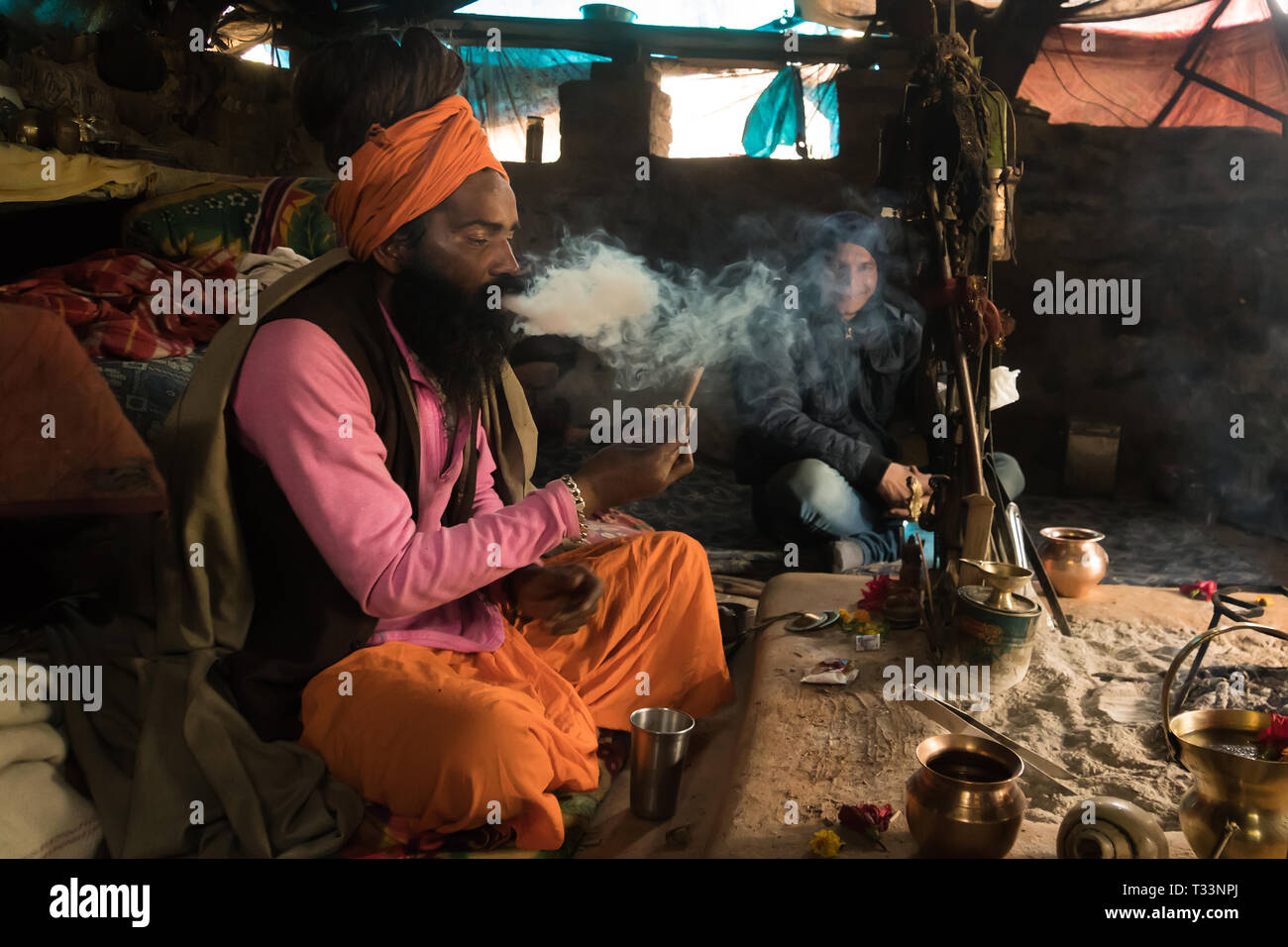 Goa, INDIA - January 11, 2018: hermit sadhu smokes a narcotic compound sitting in a hut emitting a large tangle of smoke. Babba ascetic lives in poor  Stock Photo