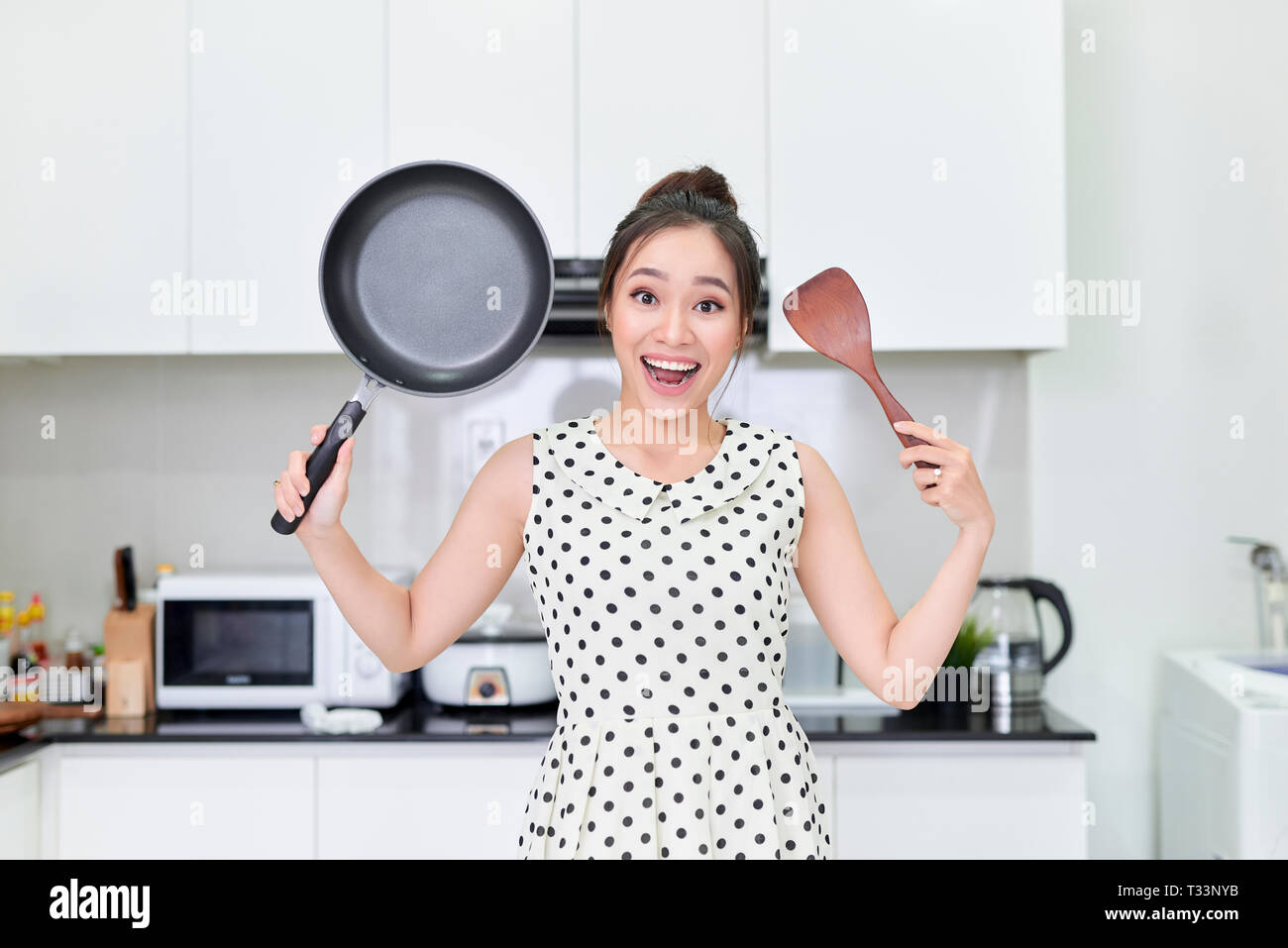Young woman showing a pan and a spatula Stock Photo