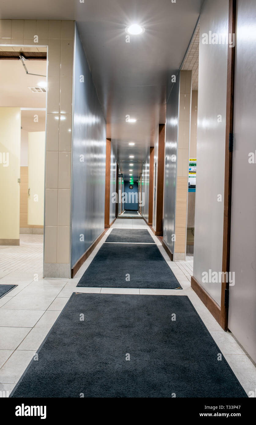 Shiny and clean hallway in mens locker room illuminated with bright LED lights along carpeted