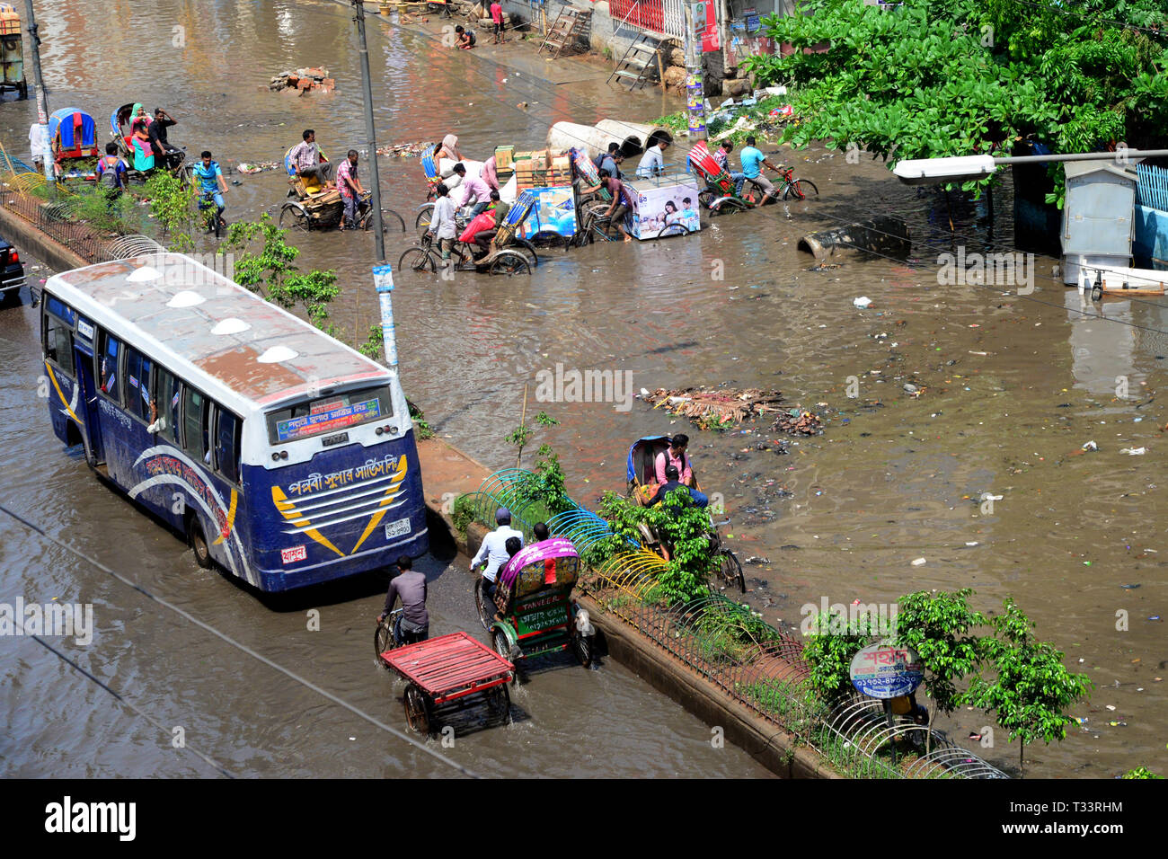 Vehicles and Rickshaws try driving with passengers through the waterlogged streets of Dhaka after heavy rainfalls caused almost-standstill, on April 6 Stock Photo