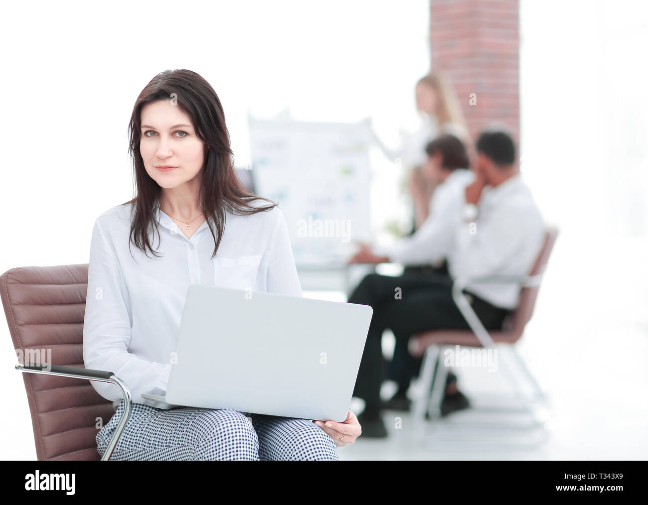 serious business woman with laptop sitting in the lobby of the office ...