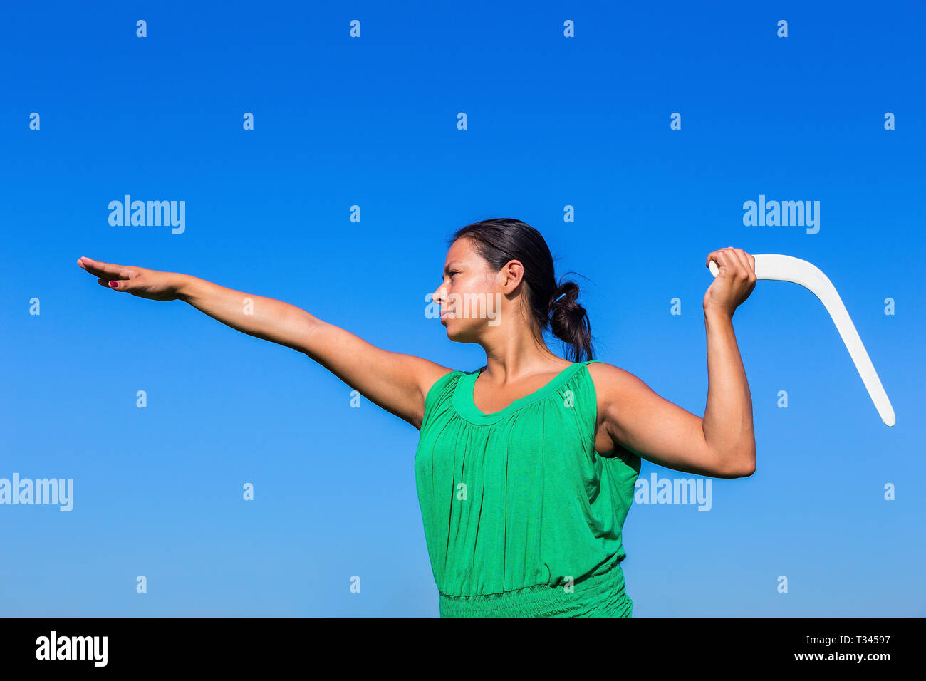 Young colombian woman throwing white boomerang in blue air Stock Photo