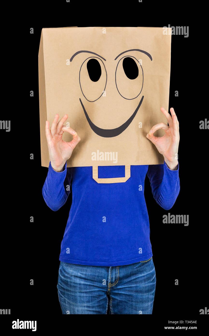 Happy woman smiling with paper bag on head isolated on black background Stock Photo