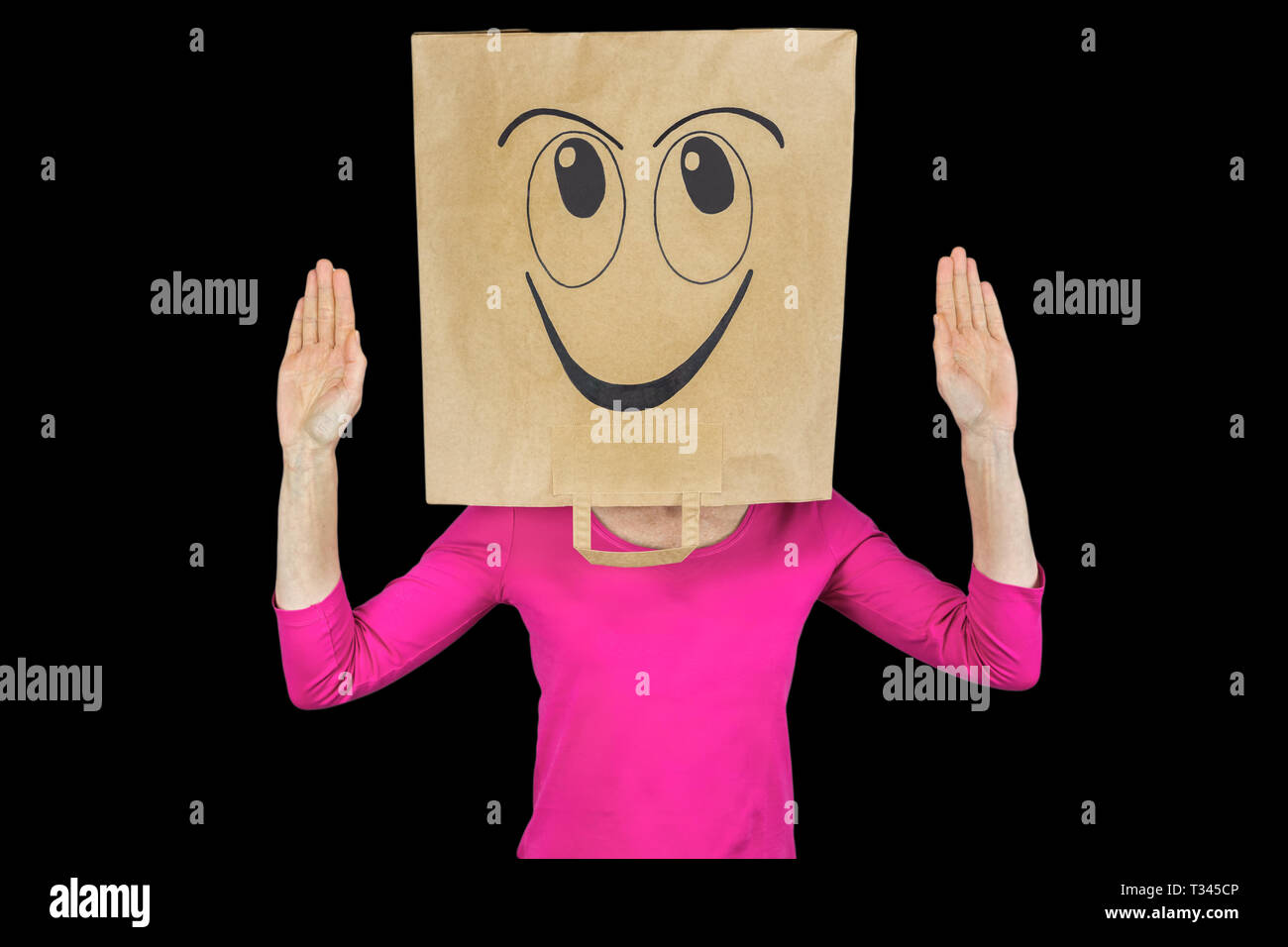 Woman wearing paper bag with face expressing happiness isolated on black background Stock Photo