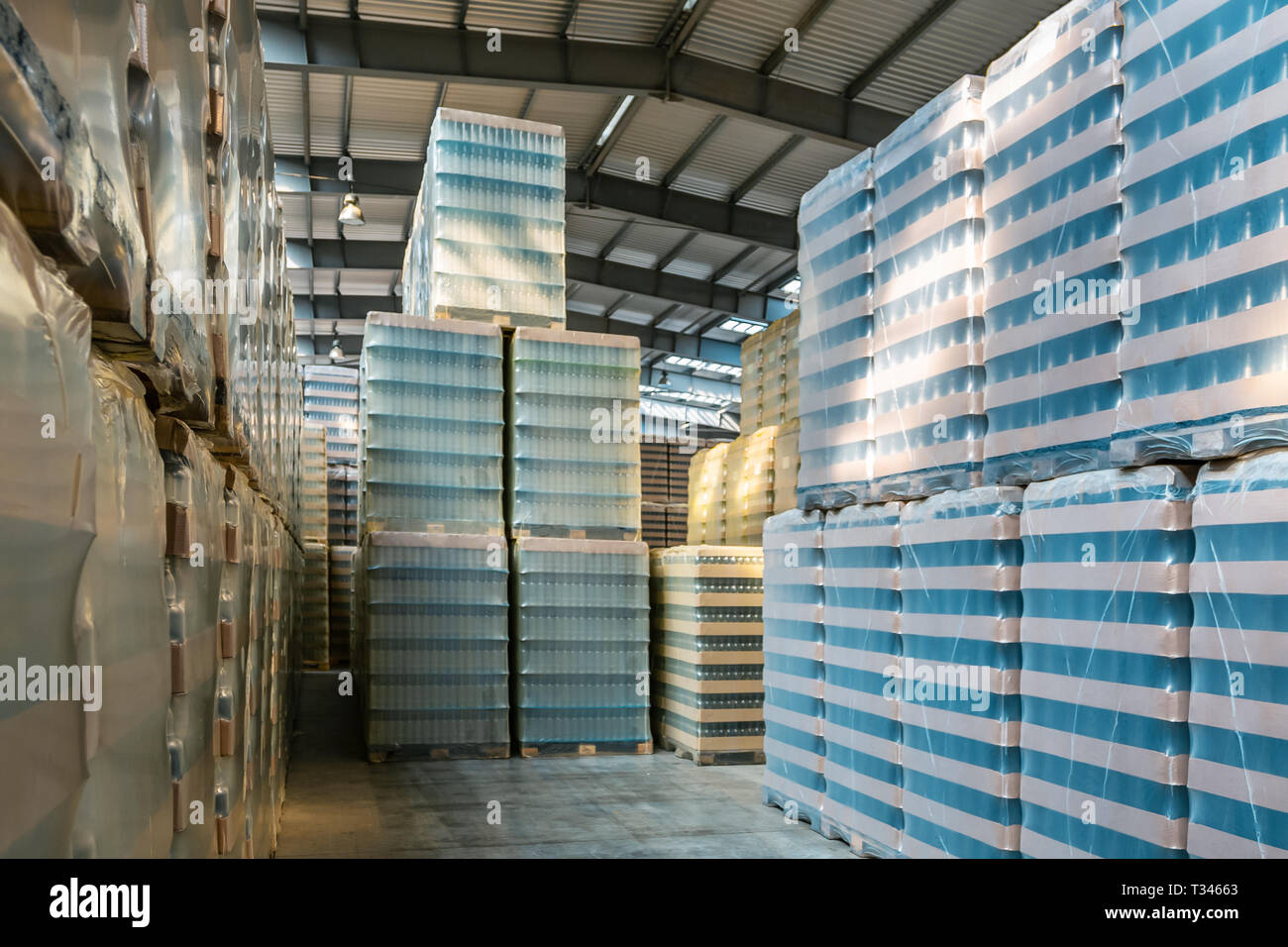 Large modern storehouse with some goods. Factory building or warehouse building with packed goods ready to ship. Warehouse with packed glass bottles.  Stock Photo