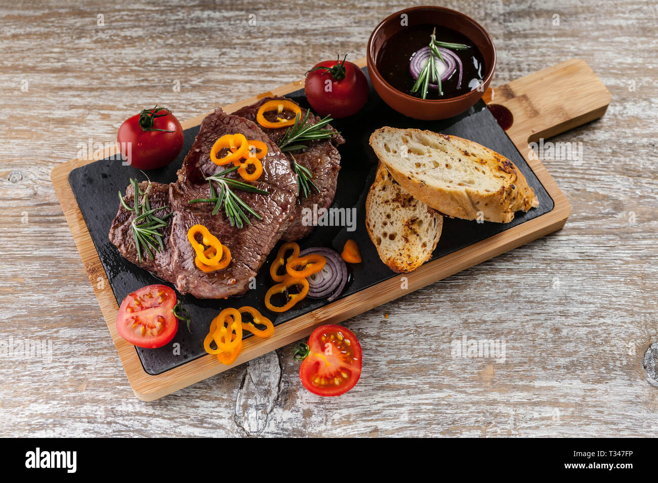 Fried Black Angus beef meat on a cutting board. Meat, spices, vegetables, croutons and rosemary Stock Photo