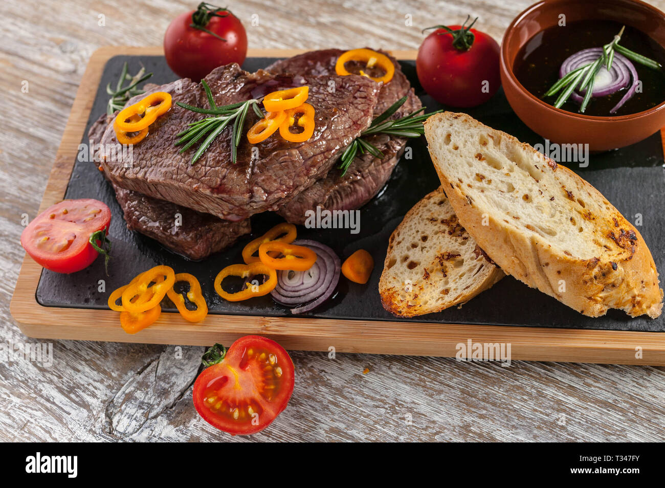 Fried Black Angus beef meat on a cutting board. Meat, spices, vegetables, croutons and rosemary Stock Photo