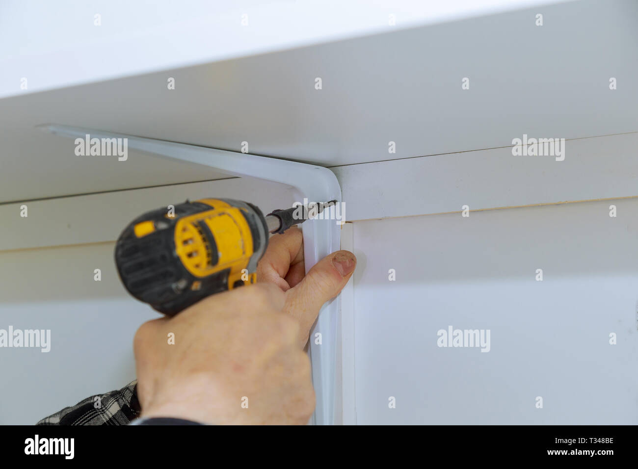 Man installing wooden shelves on brackets installation of shelves Stock Photo