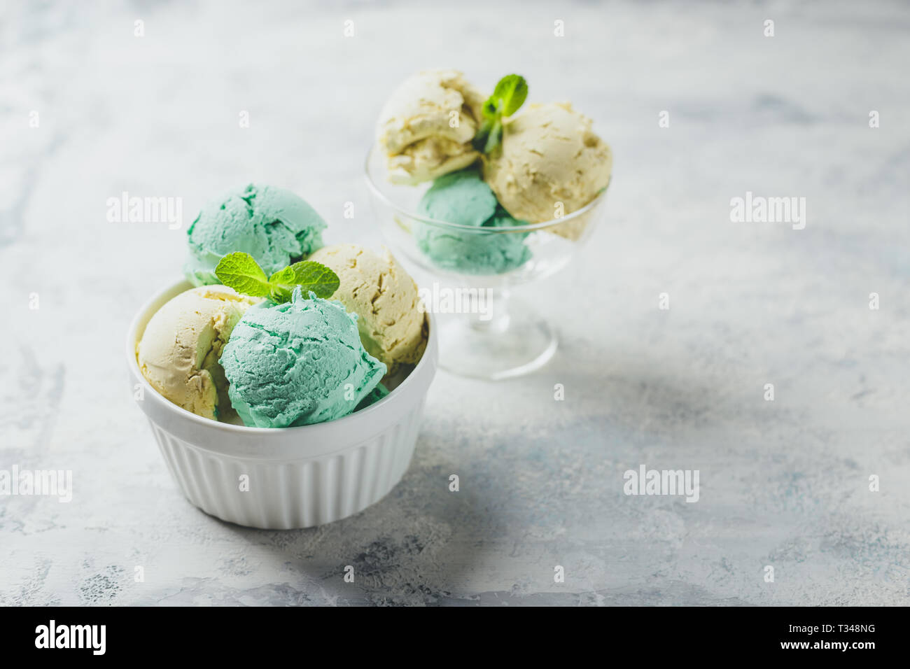 Mint and lemon ice cream with mint leaves in ceramic bowl on light background Stock Photo