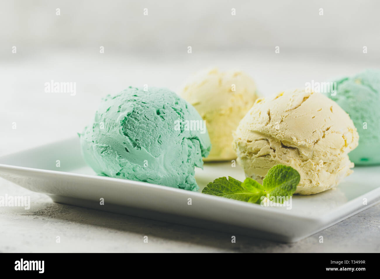 Mint and lemon ice cream with mint leaves in white plate on light concrete background Stock Photo