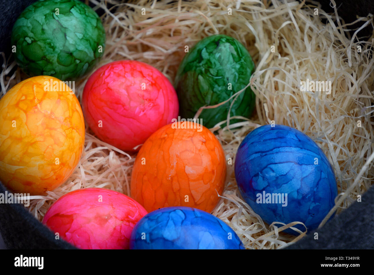 easter basket filled with white straw and colored cooked eggs, easter theme with colored eggs, happy easter background Stock Photo