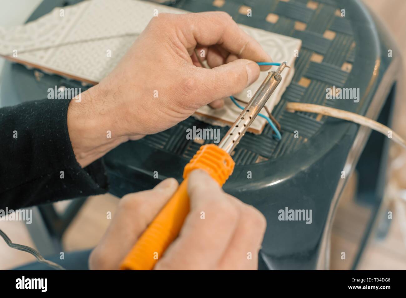 Male holding soldering iron tool repairing, electrical wire connection