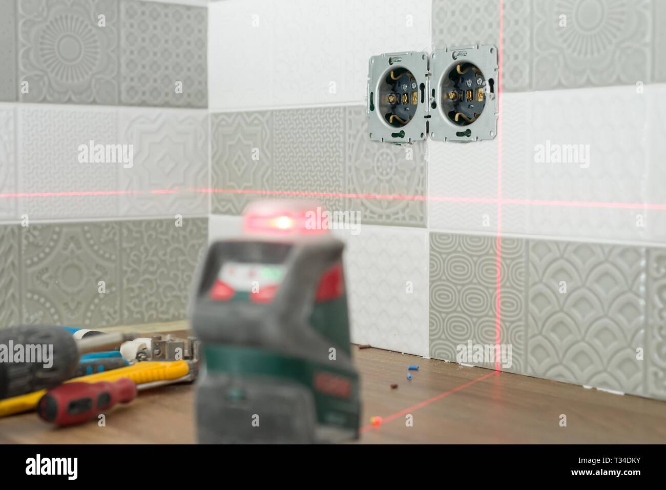Electrician using infrared laser level to install electrical outlets