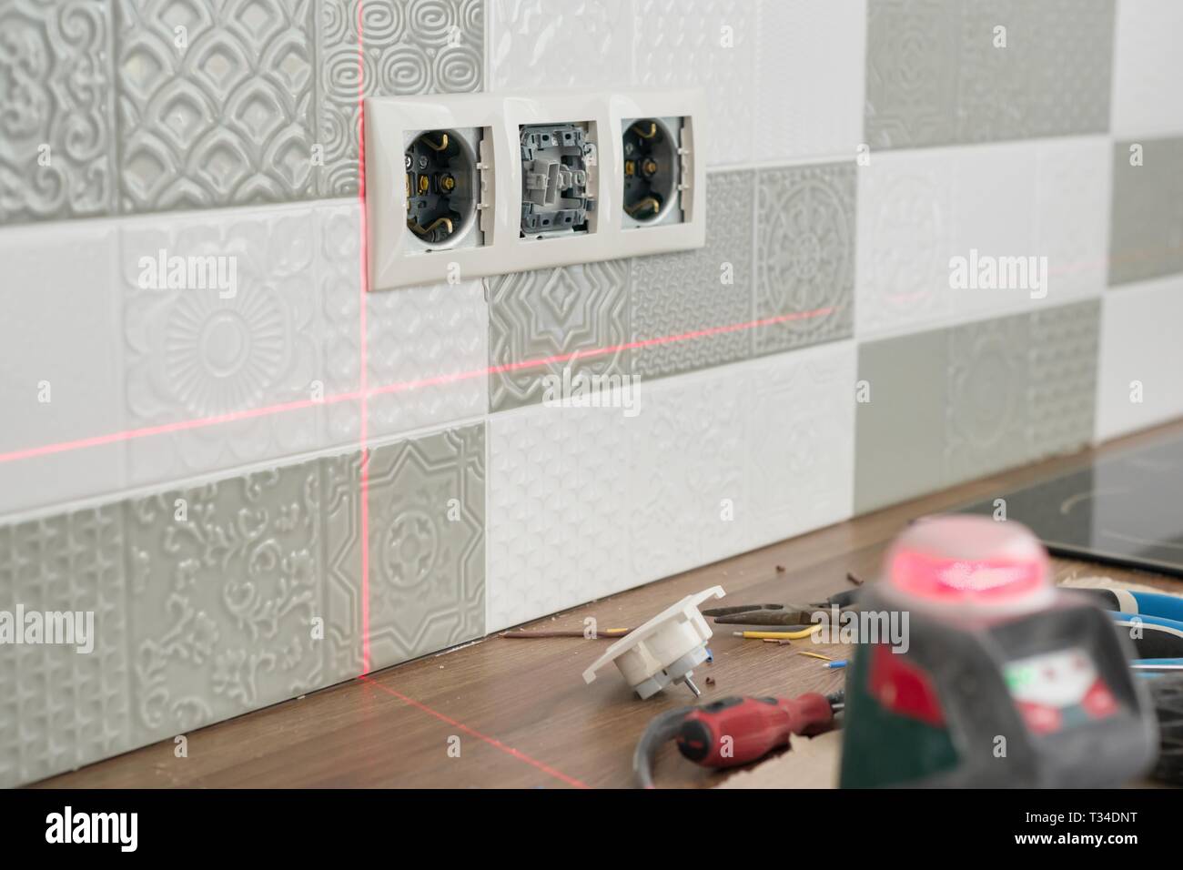 Electrician using infrared laser level to install electrical outlets