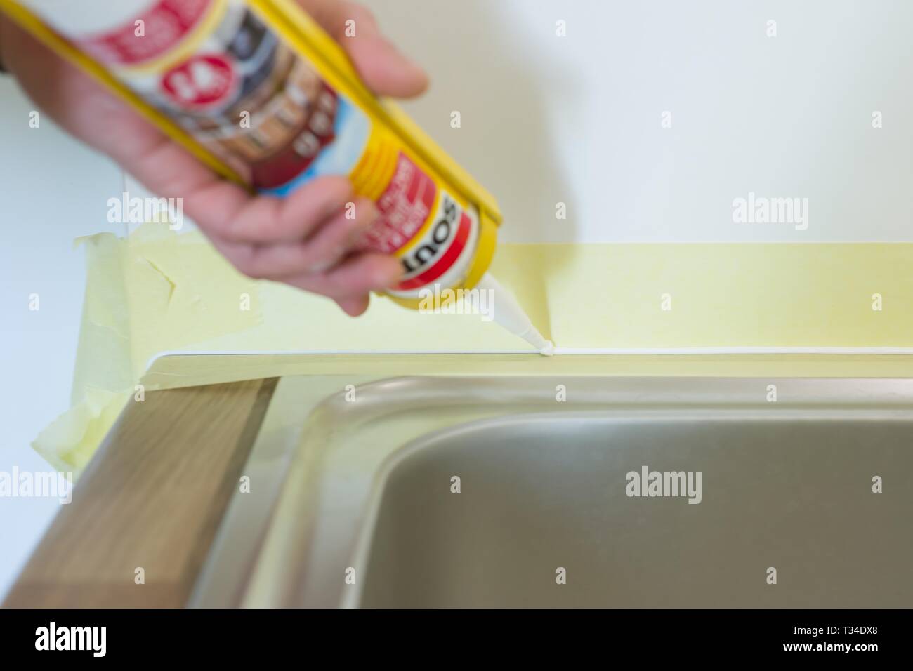 Kyiv, UA, 15032019. Worker with construction syringe fills seam between the ceramic tiles on