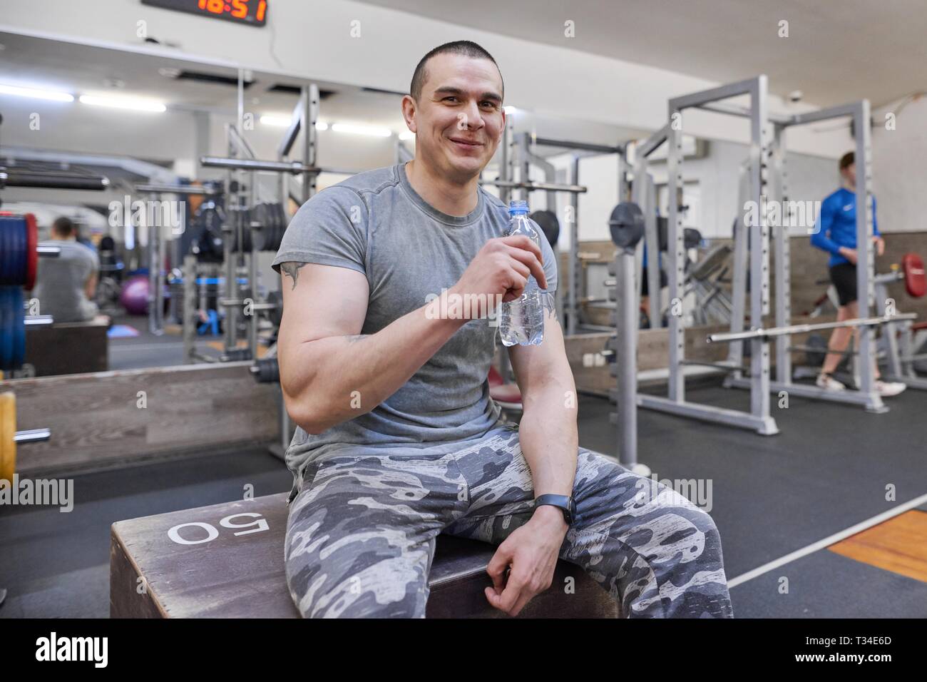 Young strong muscular man in gym drinking water from bottle Stock Photo ...