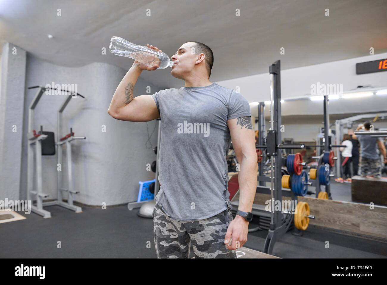 Young strong muscular man in gym drinking water from bottle Stock Photo ...