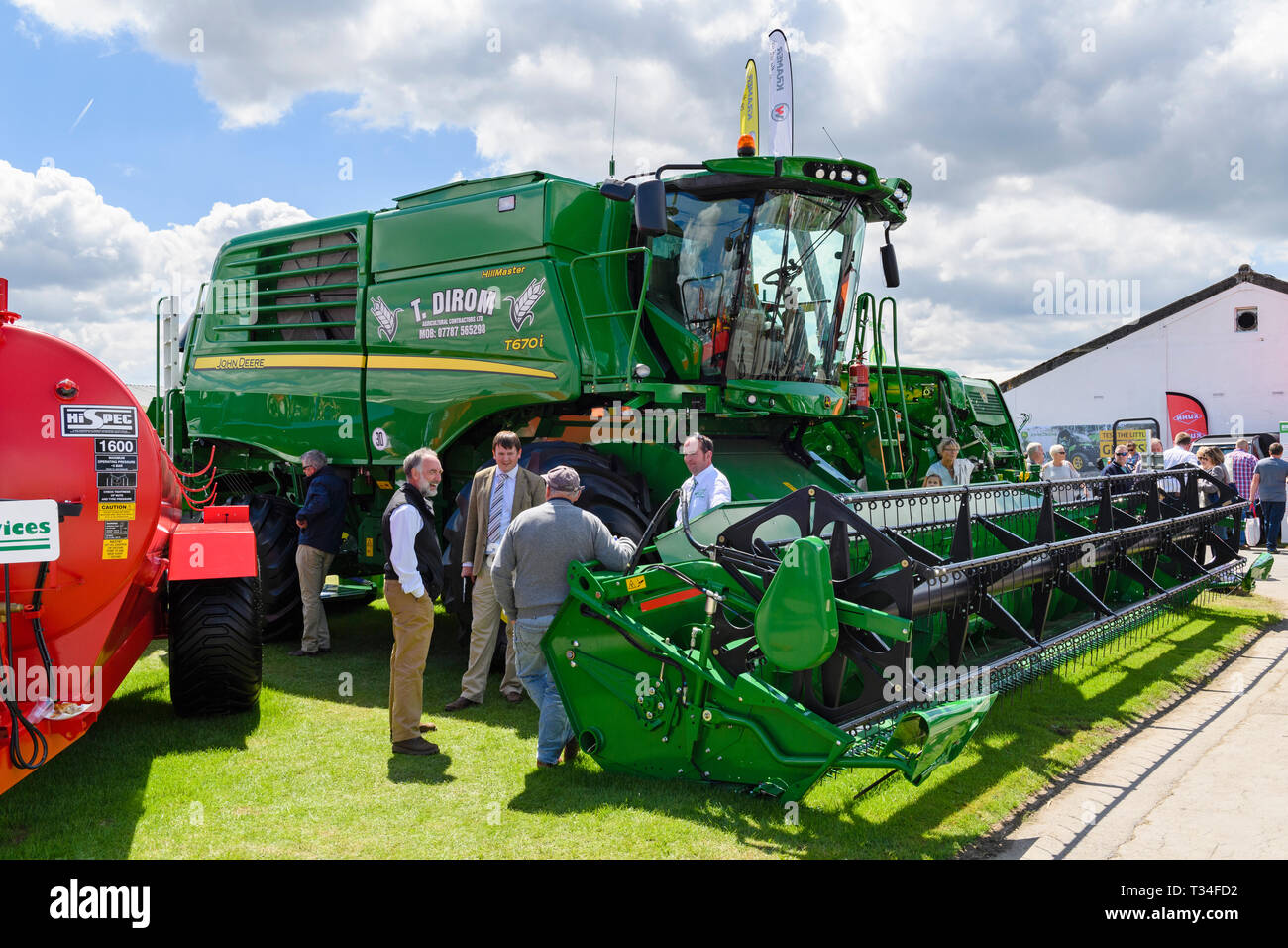 People standing & looking at agricultural machinery (green combine harvester) by trade stand display - Great Yorkshire Show, Harrogate, England, UK. Stock Photo