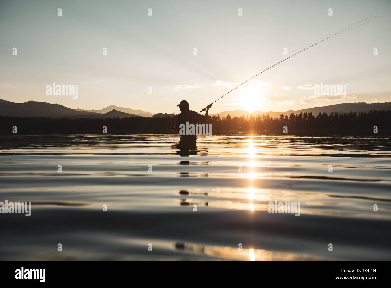 Silhouette of a man standing in a river fly fishing, United States Stock Photo