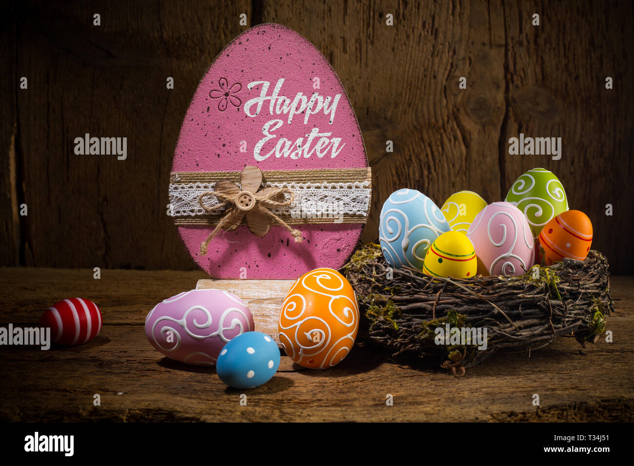 Colorful painted happy easter greeting card eggs in birds nest basket on rustic wooden old  background Stock Photo