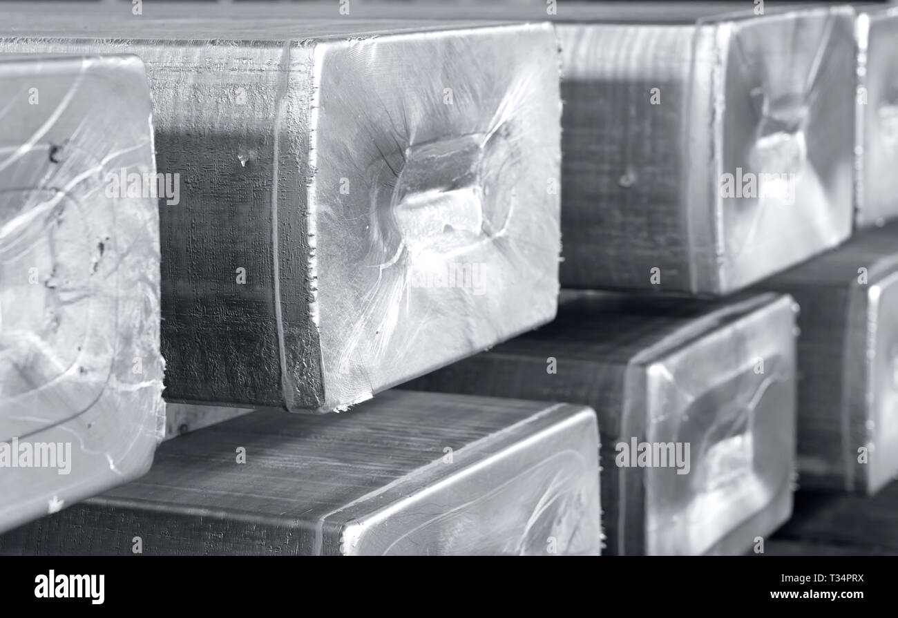 heavy aluminum ingots stacked in a warehouse foundry, raw material to be processed in a hot mill. Photo in black and white with bluish tone Stock Photo
