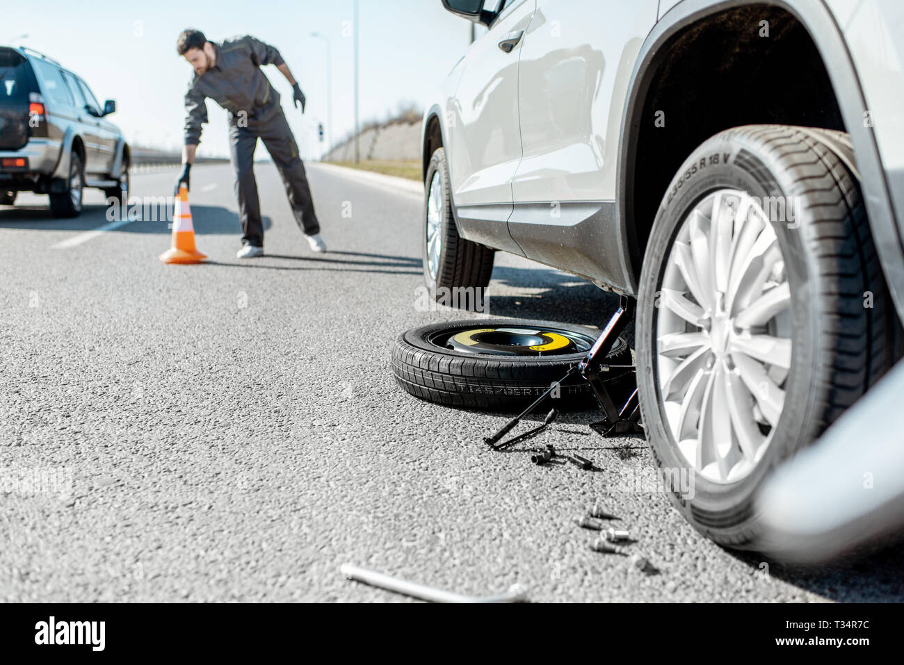 Road assistance worker putting emergency cones near the broken car on the  highway Stock Photo - Alamy