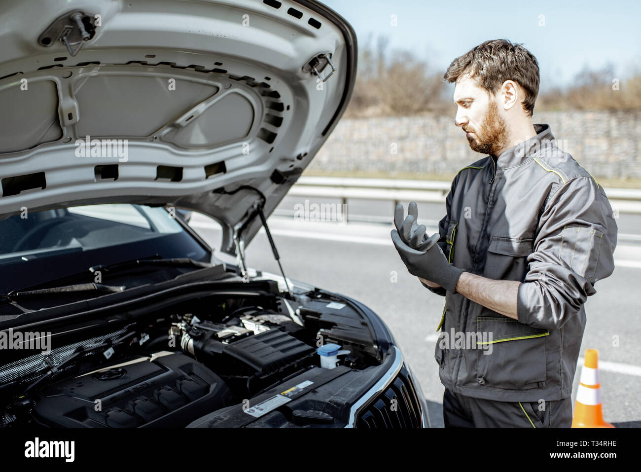 Handsome auto mechanic or road assistance worker in uniform repairing