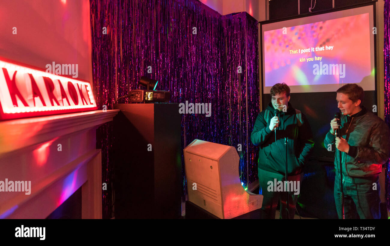 London, UK. 6 April 2019. Visitors enjoy Malapropic Karaoke by Common  Works, a randomly generated sound-alike karaoke, at "Now Play This", a  festival of experimental game design. Favourite song lyrics are replaced