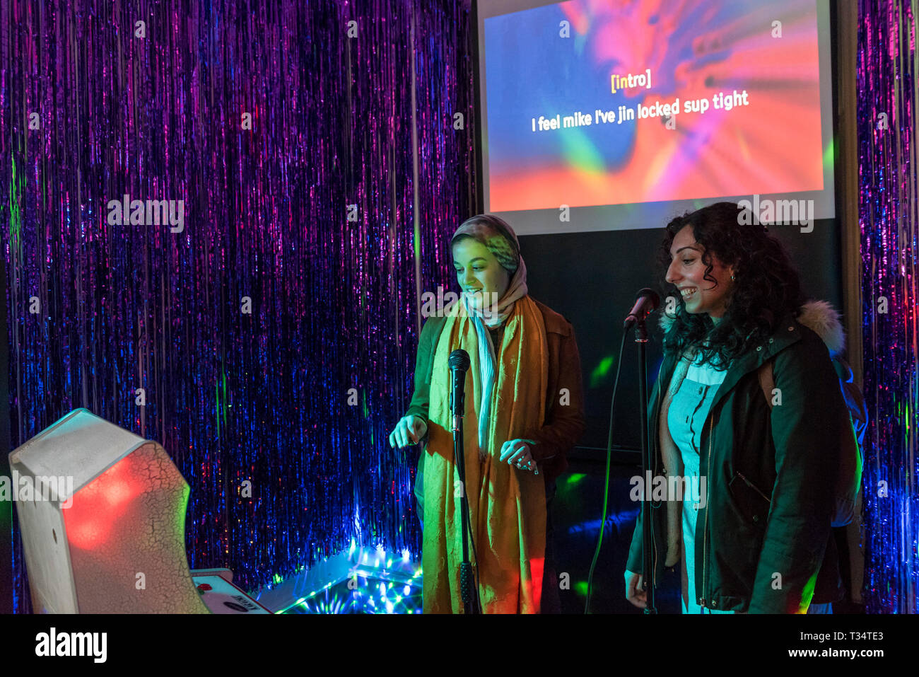 London, UK. 6 April 2019. Visitors enjoy Malapropic Karaoke by Common  Works, a randomly generated sound-alike karaoke, at "Now Play This", a  festival of experimental game design. Favourite song lyrics are replaced
