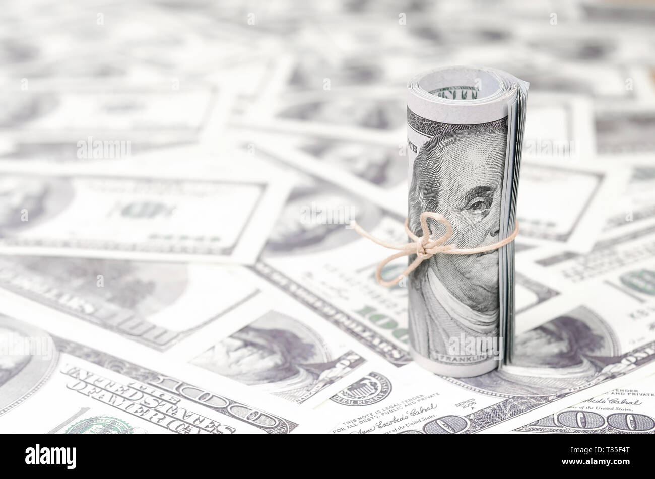 US dollars rolled up and tightened with band lies on a lot of american banknotes with blurred