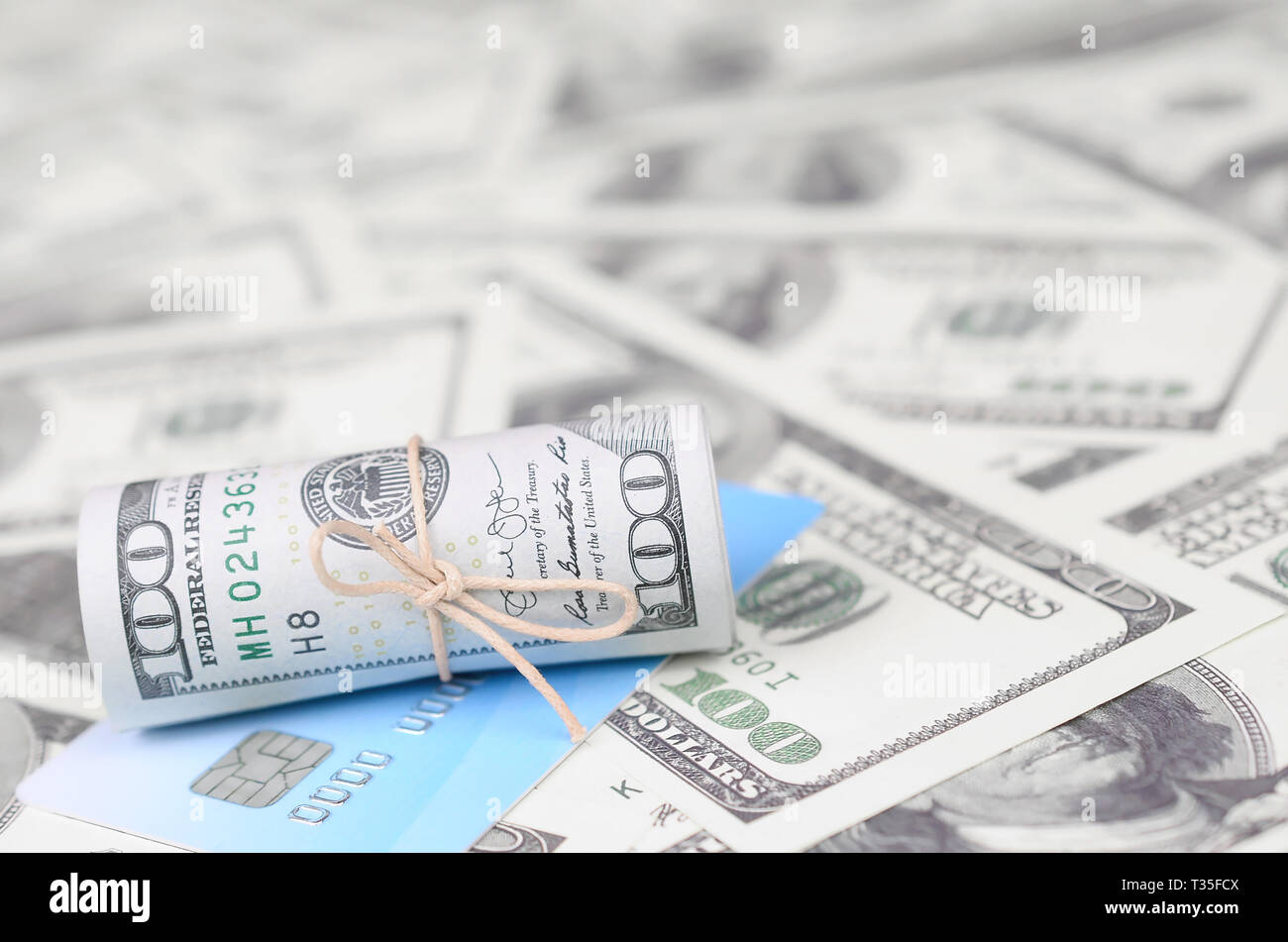Us Dollars Rolled Up And Tightened With Band Lies On Credit Card