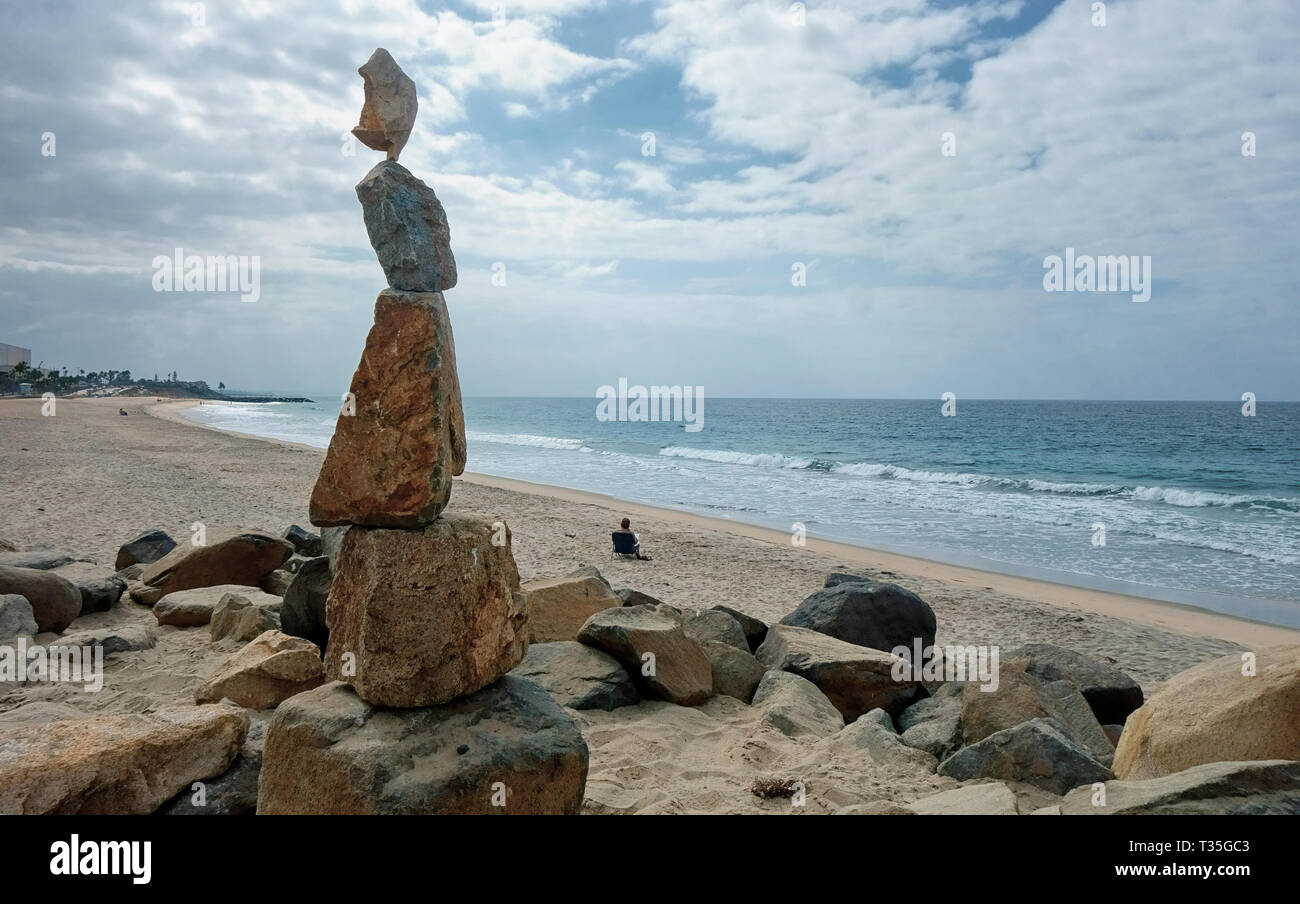Stacked rocks in the shape of a woman looking out across the beach to ...