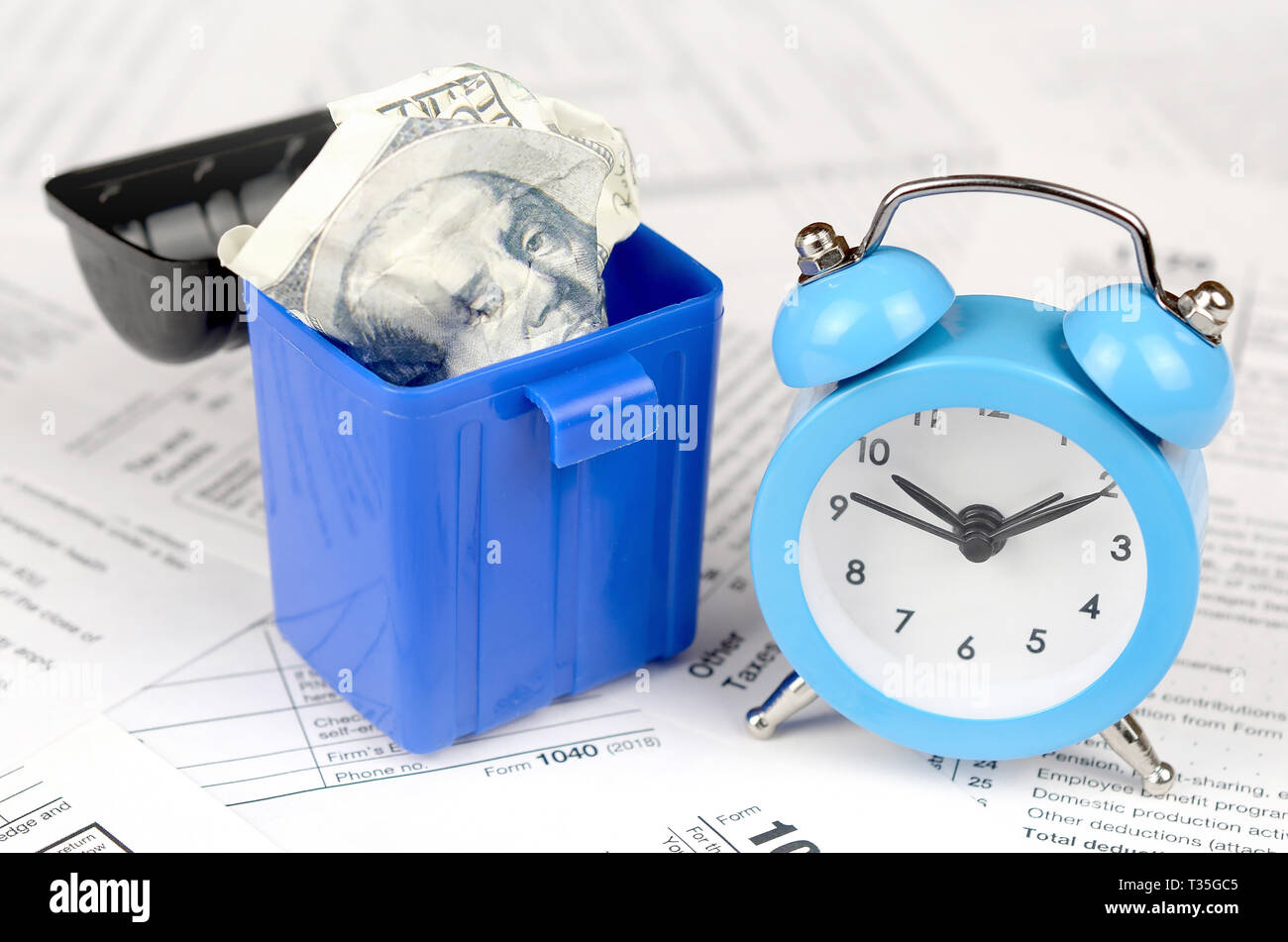 Many american tax blank forms with blue alarm clock and crumpled