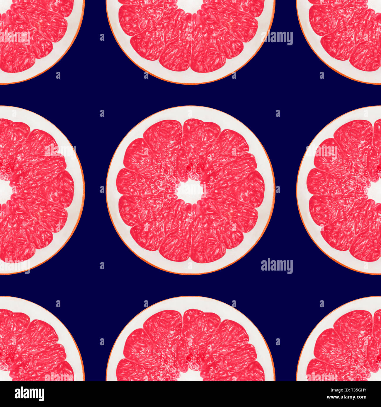 Large pink grapefruit halves on a dark blue background Stock Photo