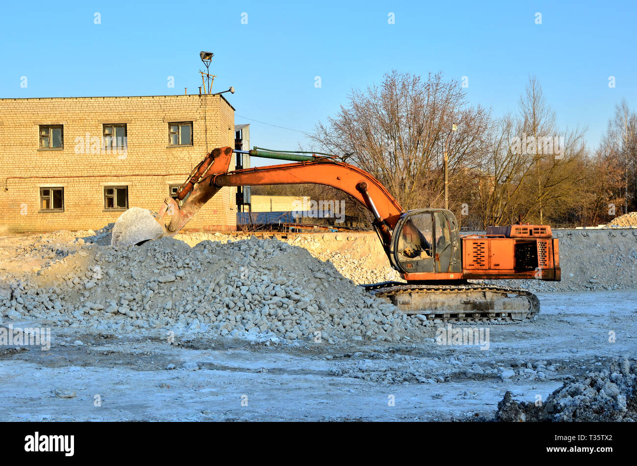 Orange excavator working on an industrial building site, loading ...