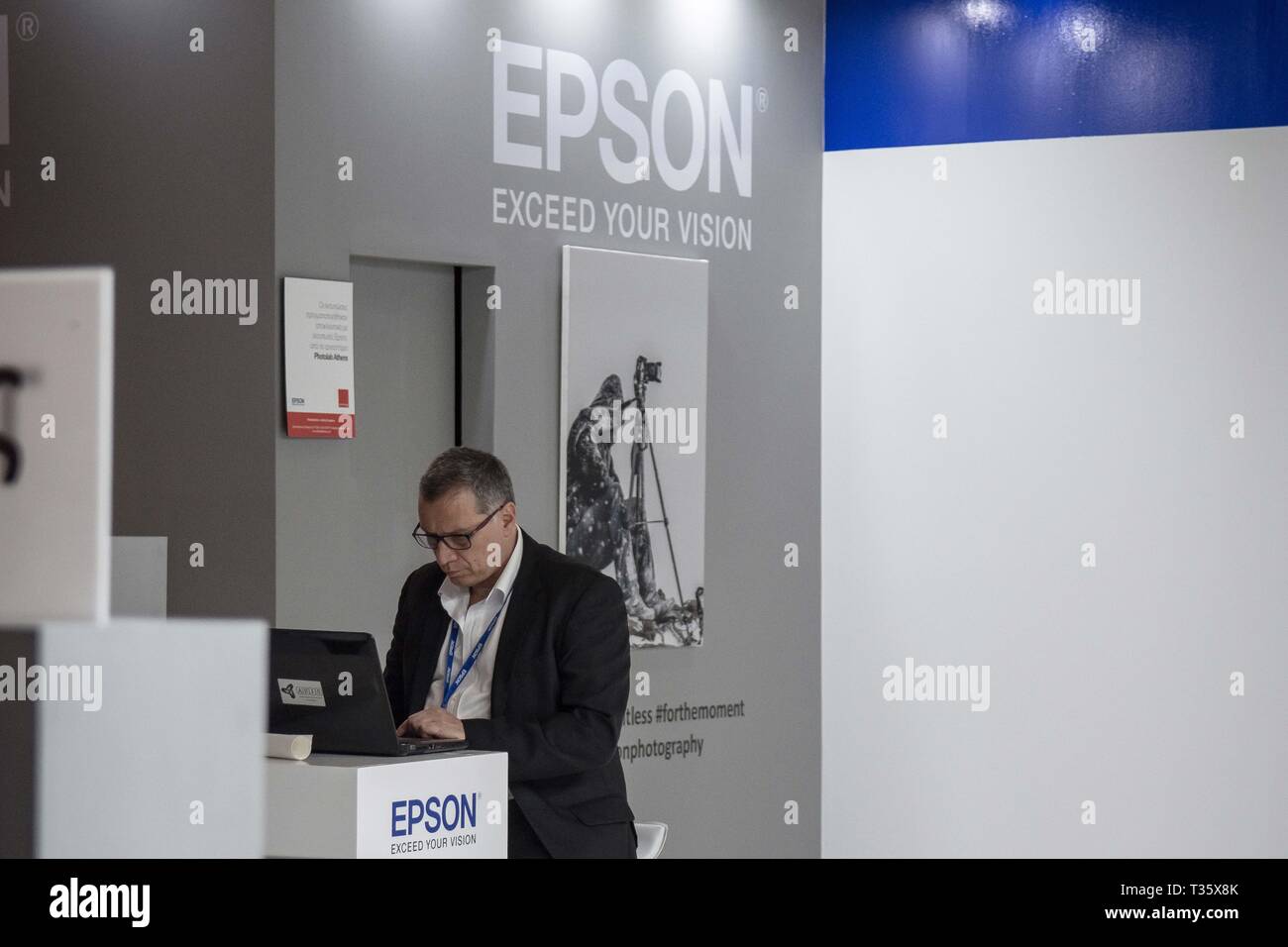A man seen looking at his laptop in front of the Epson store during the festival. Image +Tech & Photo vision 2019 is a big festival with large corporate delegations, many exhibitions, stores and workshops about photography and video was held In the place of Helexpo Marousi in Athens, Greece. Stock Photo