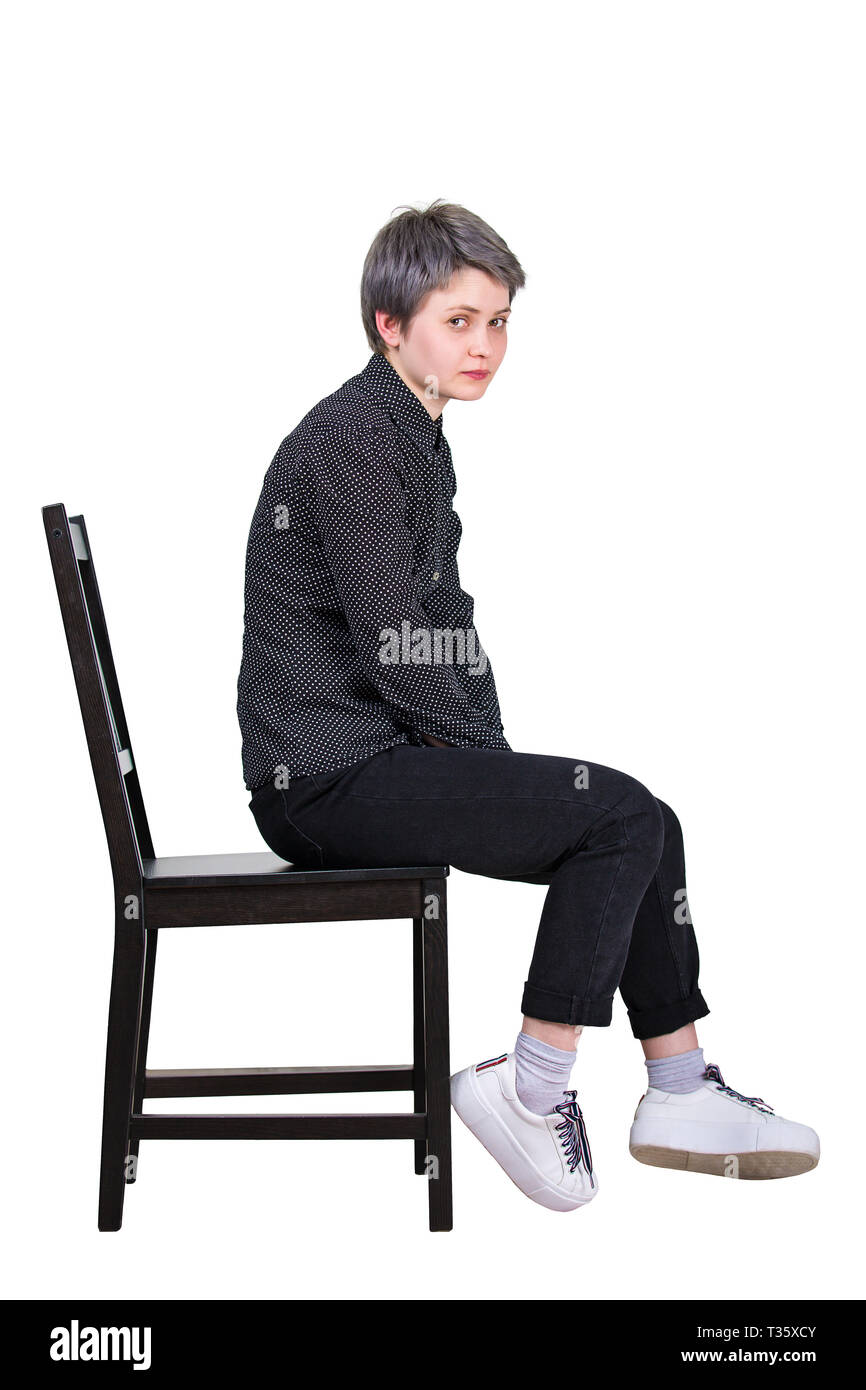 Side view full length portrait of tired young woman seated on a chair looking disappointed to camera isolated over white background. Stock Photo