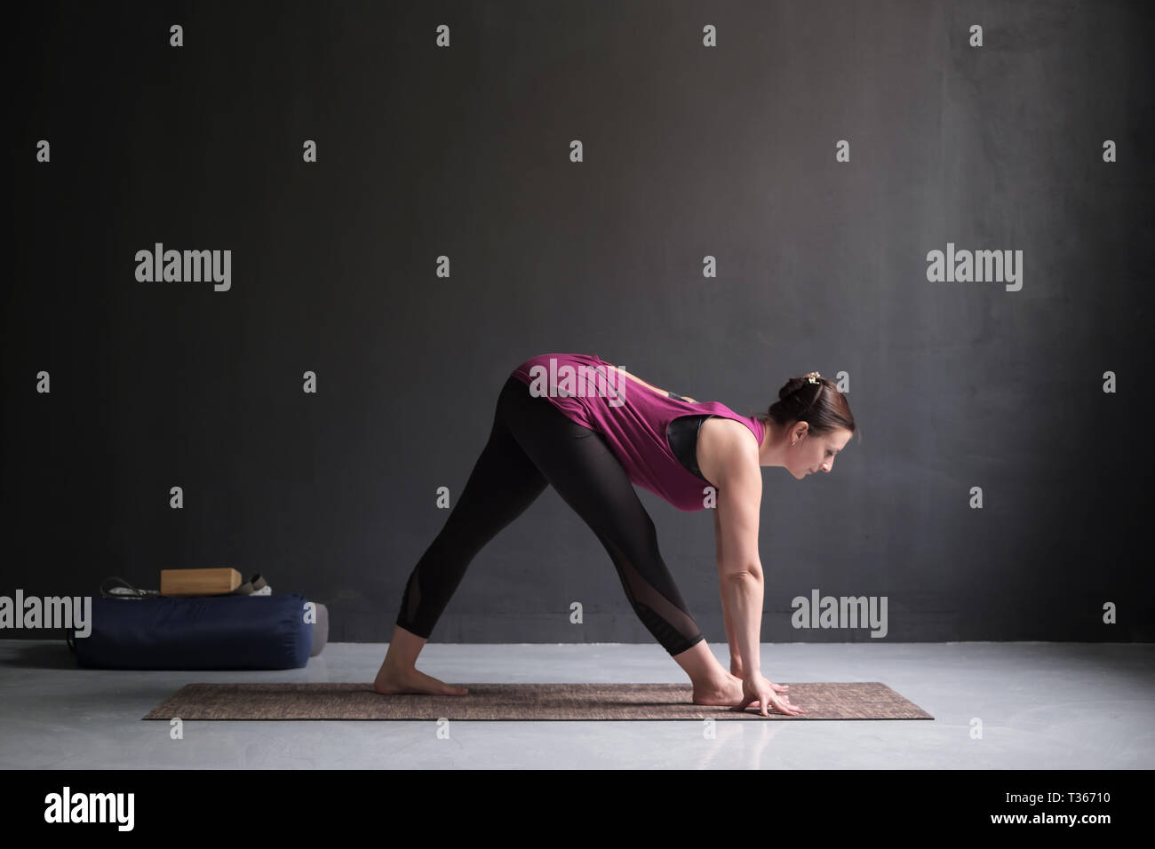 Sporty young woman practicing yoga, doing Half Pyramid or Parshvottanasana, working out. Studio full length Stock Photo