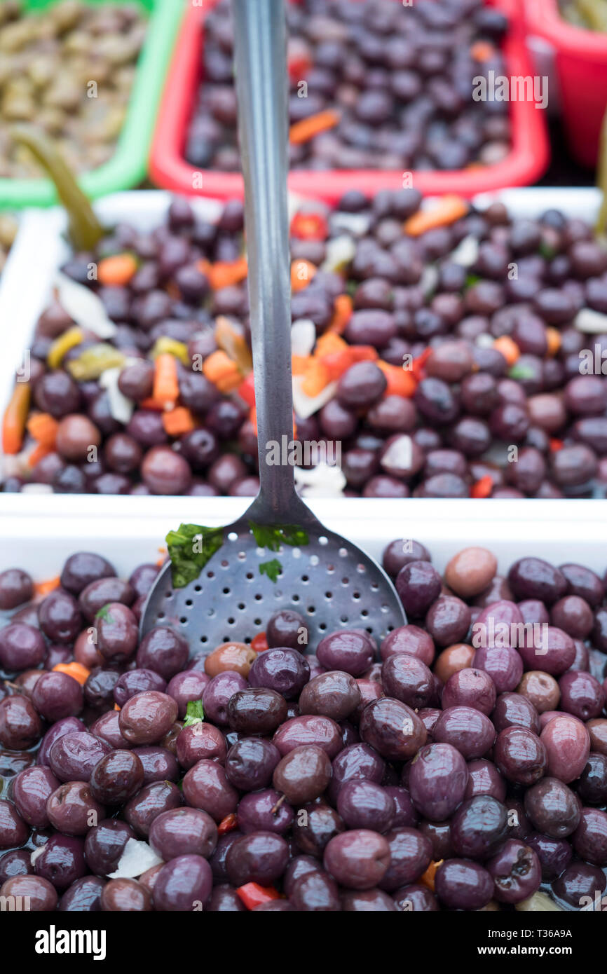 Italian black olives on display with scoop for sale on market stall at