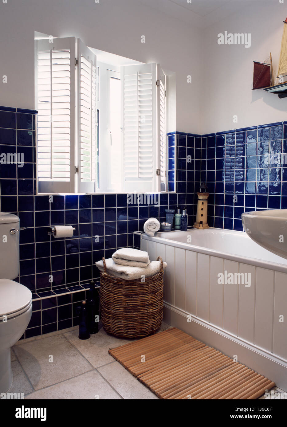 White plantation shutters in bathroom with blue tiling Stock Photo