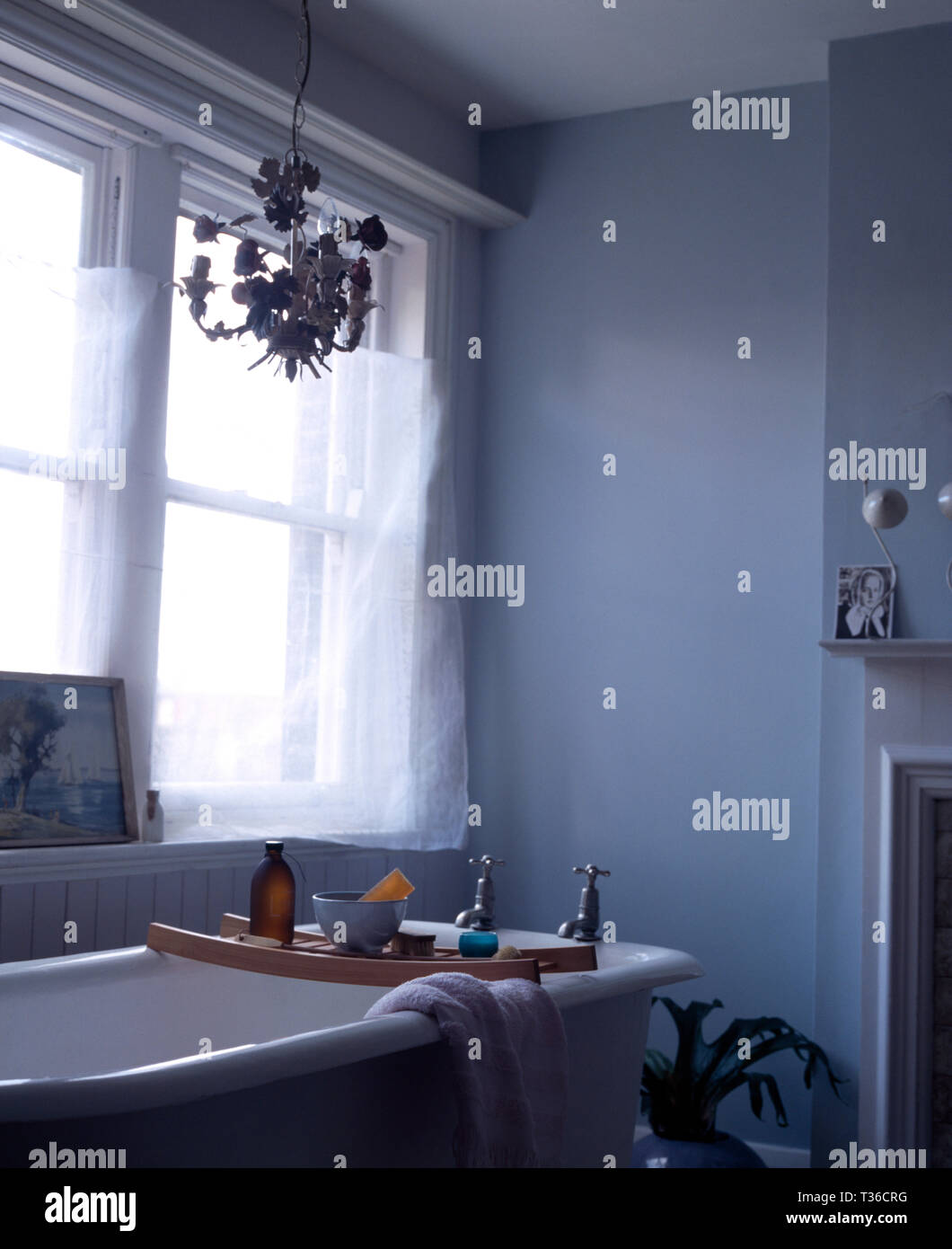 Roll top bath with wooden rack in pale blue bathroom Stock Photo - Alamy