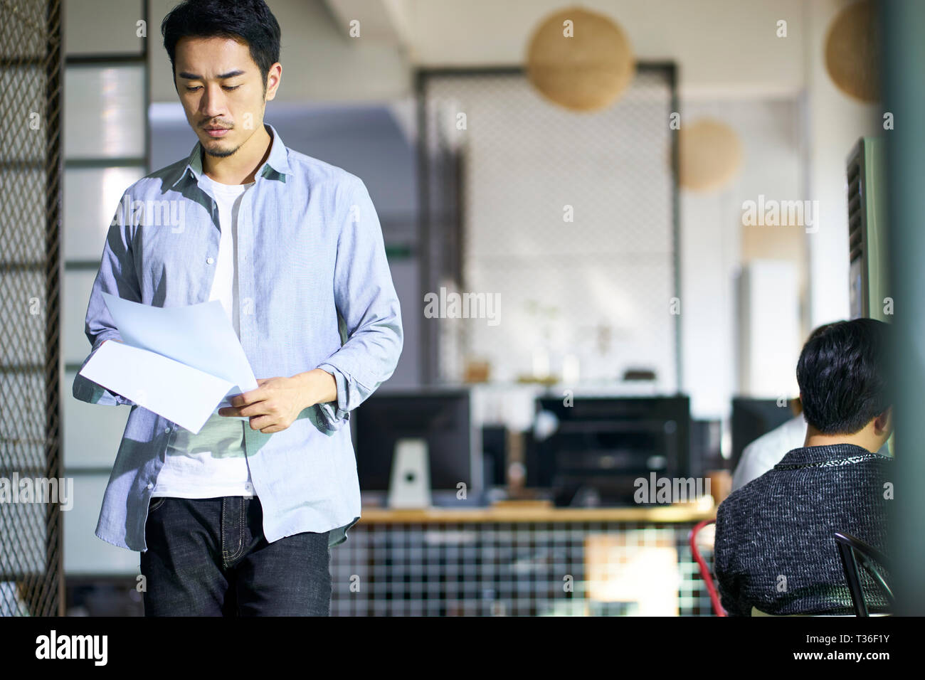 young asian business man reviewing document while walking in office. Stock Photo