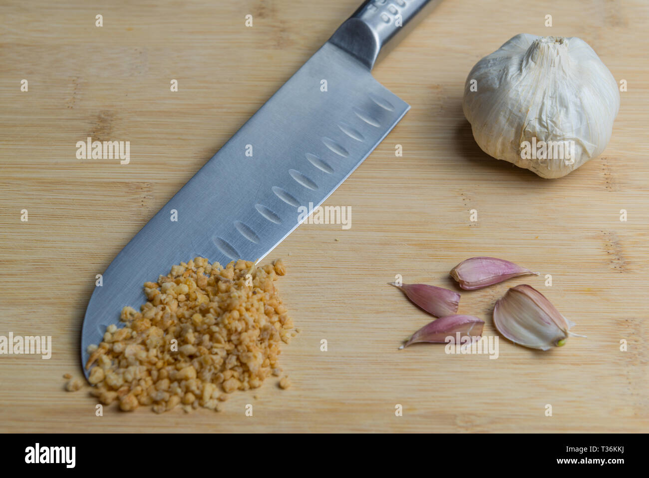 Japanese kitchen knife ( Santoku ) on a cutting board with dried garlic