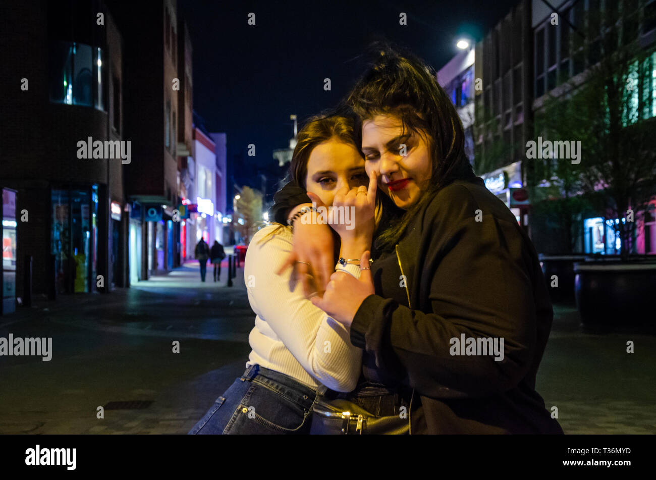 A couple of young women pose for a portrait in Peascod Street, Windsor, UK on a Saturday night. Stock Photo